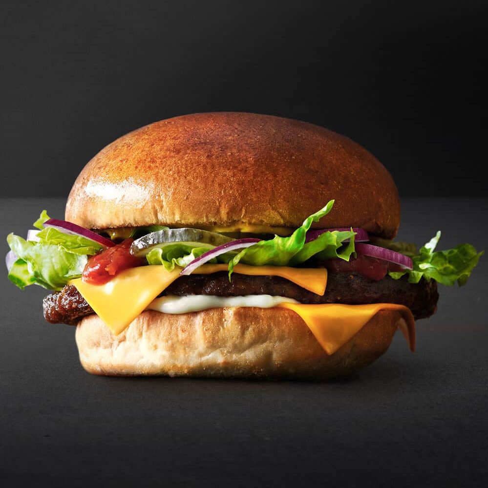 En lækker brioche burger med dobbelt ost, serveret med saftig bøf og grøntsager