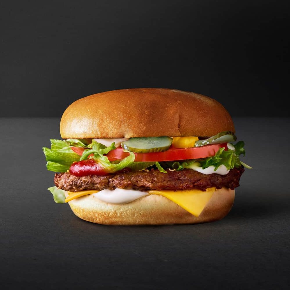 Cheeseburger Deluxe: En lækker cheeseburger med saftig oksekødspatty, smeltet ost, friske grøntsager og saucer, serveret i en brioche bolle